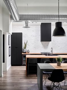 an open kitchen and dining room with white brick walls, black appliances and wooden floors