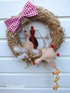 a chicken and hen wreath hanging on the side of a building with a red gingham bow