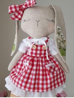 a stuffed animal wearing a red and white checkered dress on top of a table