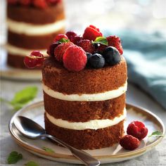 there is a cake with berries on top and white frosting in the middle, sitting on a plate