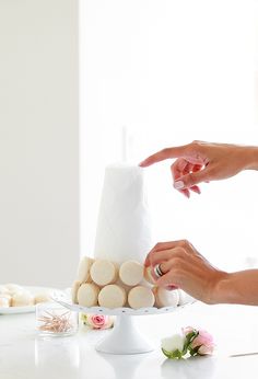 two women are decorating a cake with white frosting and flowers on the table