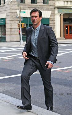 a man in a suit is standing on the sidewalk