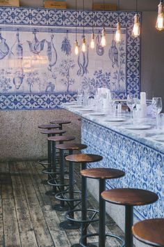 a restaurant with blue and white tiles on the wall, wooden bar stools and wood flooring