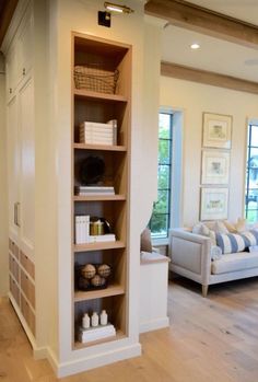 a living room filled with furniture and a book shelf next to a couch in front of a window