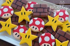 some cookies decorated like mario bros are on a white plate with yellow stars and chocolate