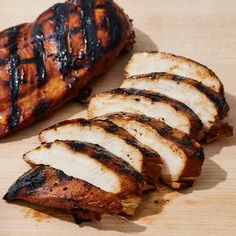 grilled chicken slices on a cutting board next to another piece of cooked meat and seasoning