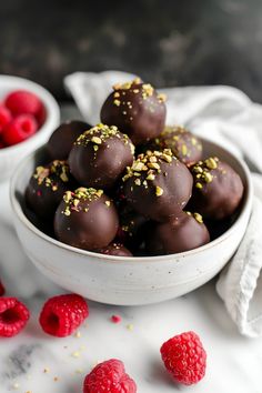 a white bowl filled with chocolate covered raspberries