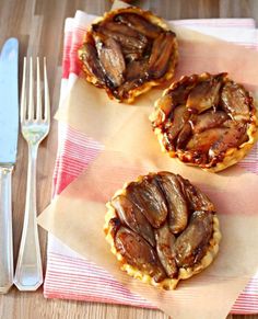 three pecan tarts sitting on top of a table next to a fork and knife