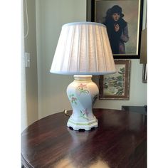 a lamp sitting on top of a wooden table next to a framed photo and painting