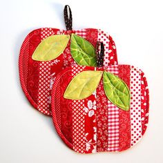 two red apples with green leaves on them sitting next to each other in front of a white background