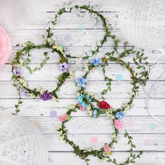 three flower crowns are laid out on a white wooden table with confetti cups