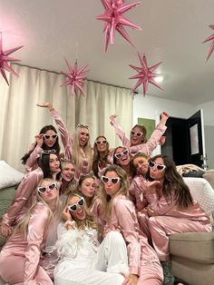 a group of women in pink pajamas posing for a photo with star decorations hanging from the ceiling