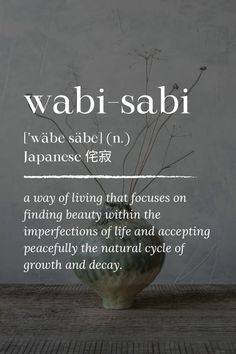 the words wabi sabi written in japanese on a table with a vase filled with flowers