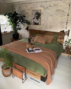 a large bed sitting next to a plant in a bedroom on top of a hard wood floor