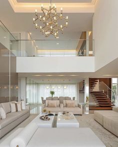 a living room filled with lots of furniture and a chandelier hanging from the ceiling