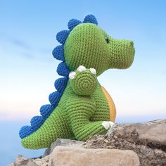 a crocheted dinosaur sitting on top of a rock