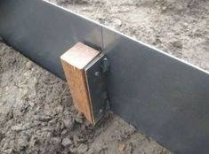 a close up of a metal and wood object on the ground with dirt behind it