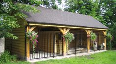 a dog house with two dogs in it and some flowers on the fence around it