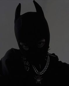 a person wearing a black mask and chain necklace