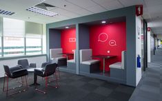 an office with red and grey walls, chairs and desks in the foreground