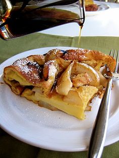 someone is pouring syrup on some food on a white plate with silverware and a fork