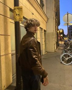 a man standing next to a pole on the side of a street near parked bikes