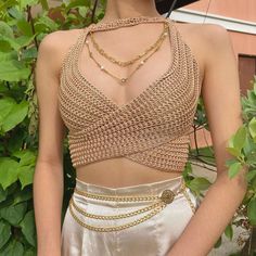 a woman wearing a gold dress with chains on it