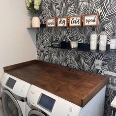 a washer and dryer in a small room with wallpapered walls behind it