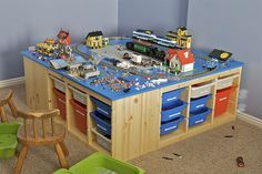 a child's play table with toy trains and cars on it in a room