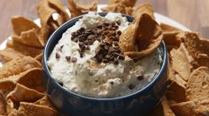 a blue bowl filled with ice cream and chips on top of a white plate covered in chocolate chips