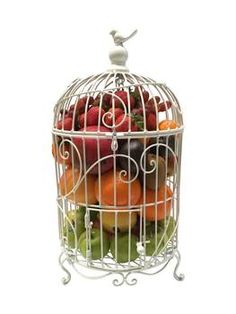 a white birdcage filled with lots of different types of fruit on top of each other