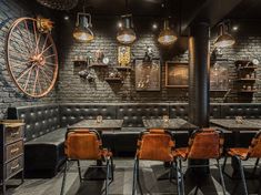 an empty restaurant with wooden tables and brown leather chairs in front of a brick wall