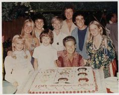 a group of people standing around a birthday cake