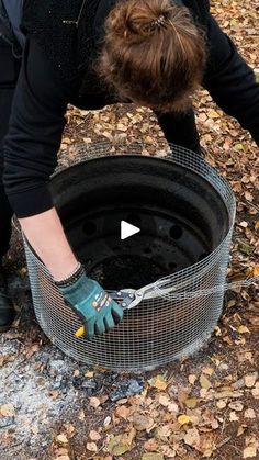 a woman bending over to pick up something out of the ground with her hands and gloves on