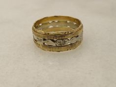 two gold wedding bands sitting next to each other on top of a white countertop