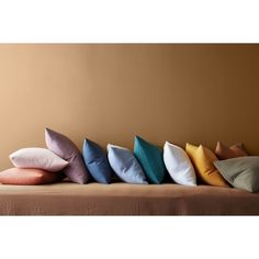 six pillows lined up on top of each other in front of a brown wall and tan walls