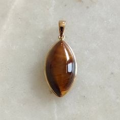 ITEM DESCRIPTION: >> The pendant is made from Solid 14K Yellow Gold. Gemstone used is absolutely natural and ethically sourced.  >> Natural Tiger Eye in Cabochon Marquise shape with bezel setting is studded on it with utmost precision.  >> This is a minimalist design and is absolutely hassle-free and everyday jewelry.  Gem: Tiger Eye Gem size: 11x21 mm  Gem weight: 11.57 carats Gold purity: 14K (58.33% approx.) Gold weight: 0.57 grams  Gross weight: 2.88 grams The Gold purity is guaranteed and it comes with authentic 14K gold hallmark. Since these Pendants are handmade, they are Nickel/Lead FREE.  CUSTOMISATION: --> Gemstone customization is available and the main gemstone can be substituted with a gem of your choice. --> You can choose your own gemstone --> Kindly drop a message for more Elegant Natural Stones Gemstones, Luxury Teardrop Cabochon Jewelry, Gold Cabochon Gemstones For Formal Occasions, Luxury Yellow Gold Pendant Gemstones, Elegant Gold Gemstones With Polished Finish, Formal Gold Cabochon Gemstones, Fine Jewelry Cabochon Gemstone Pendant, Natural Gemstones For Anniversary, Gold Teardrop Gemstones For Formal Occasions