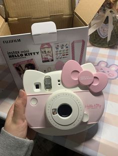 a pink hello kitty camera sitting on top of a table next to a cardboard box