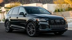 a black audi suv parked in front of a house with mountains and palm trees behind it