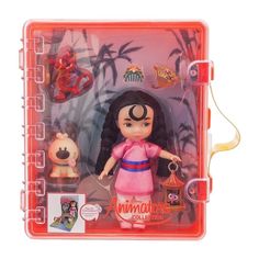 the doll is in its plastic case with other items around it, including a keychain