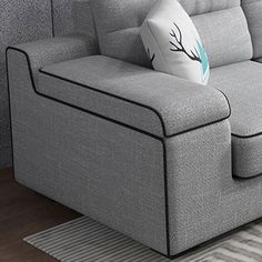 a gray couch sitting on top of a wooden floor next to a white and blue rug