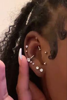 a close up of a person with ear piercings on their ears and one hand holding a cell phone