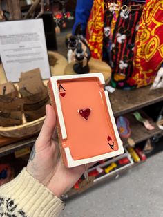 a person holding up an orange box with hearts on it in front of other items