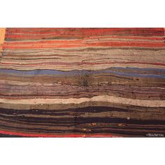 an old rug with many different colors and patterns on the ground, including stripes in blue, brown, red, orange