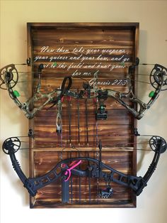 a wall mounted archery rack with arrows and bows on it's sides, in front of a wooden background