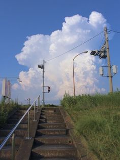 the sky is very cloudy and there are some stairs going up to it with traffic lights on each side