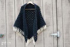 a crocheted shawl hanging up on a wooden wall next to a hook