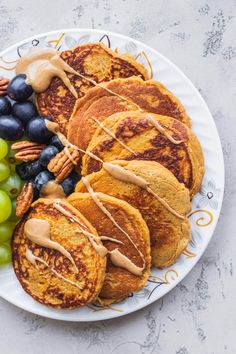 a plate with pancakes, grapes and pecans on it