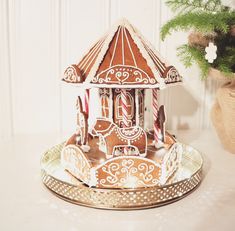 a gingerbread carousel sits next to a potted plant