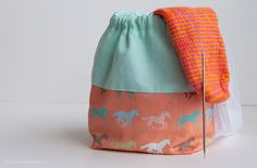 an orange and blue bag with horses printed on the side, sitting on a white surface